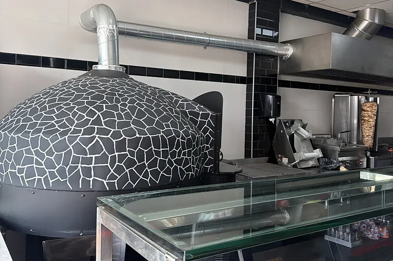 De oven met de zwart-witte mozaïekkoepel, achter de glazen toonbank